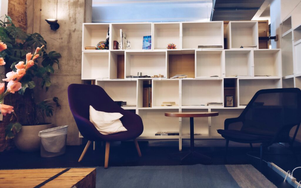 A stylish living room featuring modern furniture, bookshelves, and decorative plants.