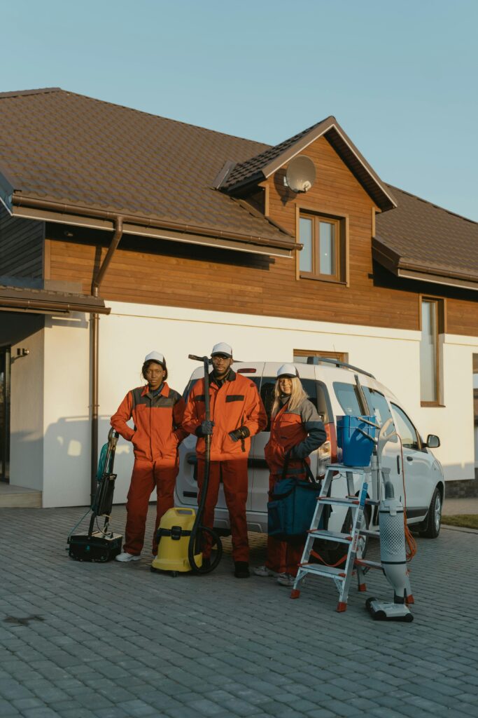 pexels-photo-6196222-6196222 Cleaning crew in uniforms with equipment standing outside a modern house.