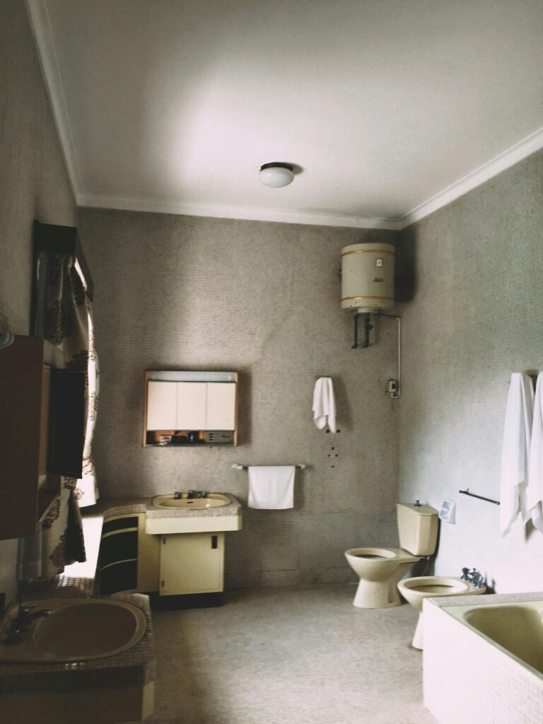 A vintage bathroom featuring a bathtub, sink, toilet, and cabinets in muted tones.