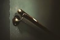 A detailed shot of a brass handrail against a dark textured wall.