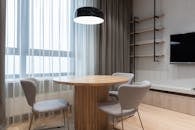Bright and minimalist living room featuring a round wooden table, modern chairs, and wall-mounted TV.
