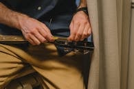 Close-up of a man restringing an acoustic guitar indoors, focusing on hand details and casual attire.